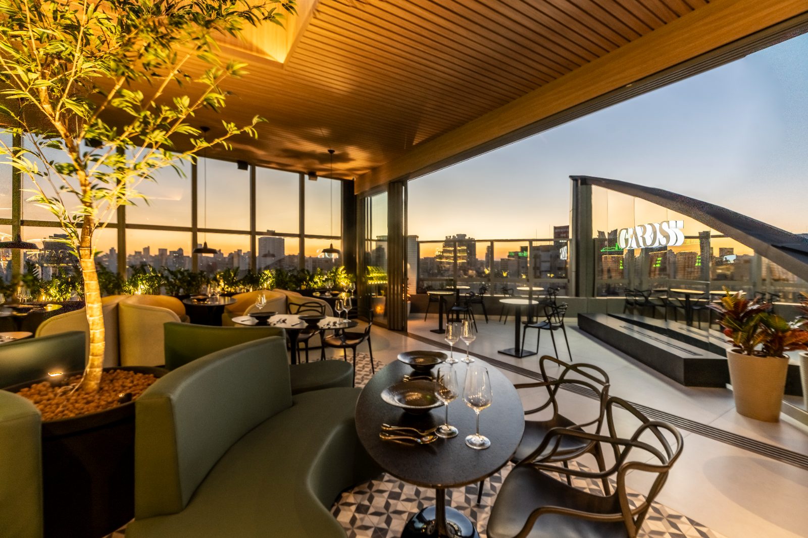 Gards Rooftop em Curitiba ao entardecer, com lounge, mesas e vista panorâmica