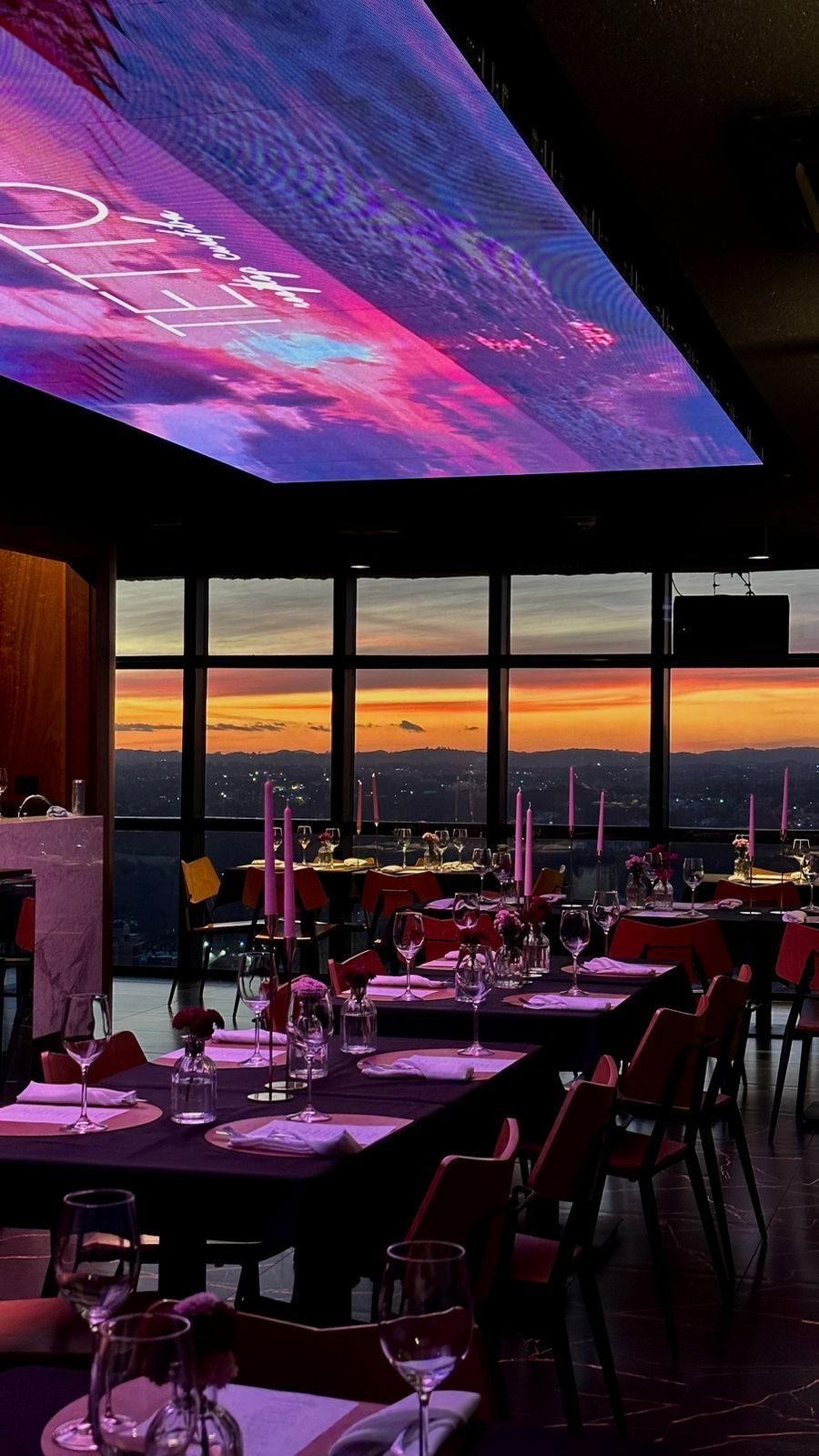 Salão do Tetto Rooftop Curitiba com painel de LED no teto e vista da cidade ao pôr do sol